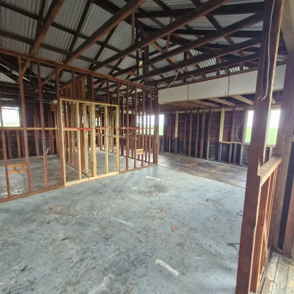 Interior of a house stripped back to exposed timber wall and roof framing